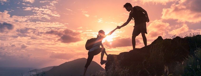 People,Helping,Each,Other,Hike,Up,A,Mountain,At,Sunrise.